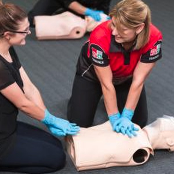Two people practising CPR on a training manikin during a first aid course