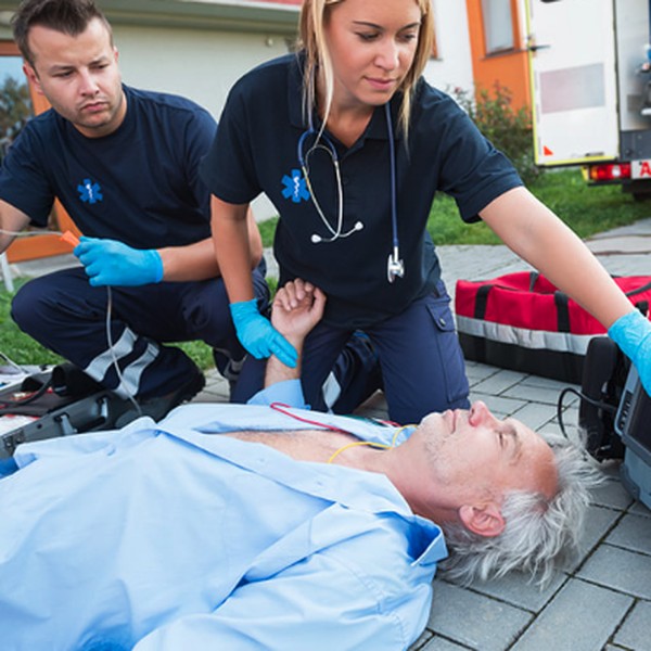 Two paramedics assessing a patient outdoors beside an ambulance during an emergency response scenario