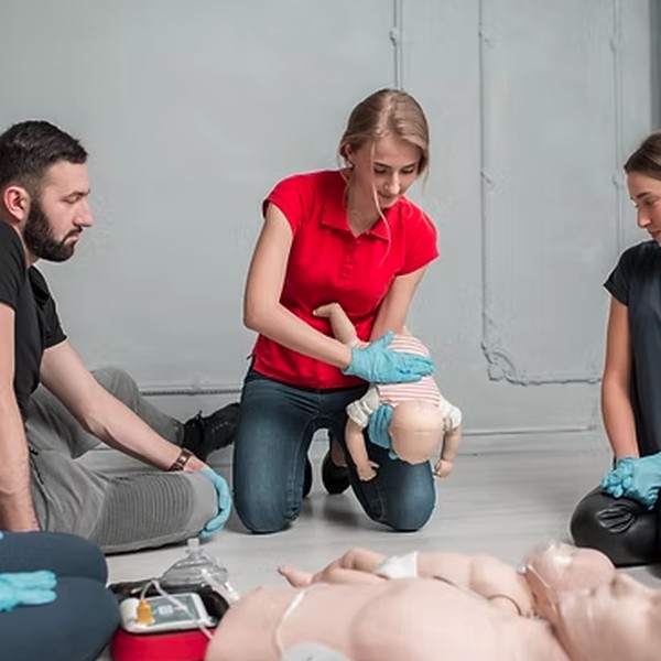 A group first aid training session practising infant CPR and AED use on training manikins